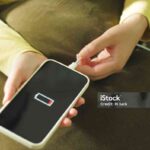Young woman charging mobile phone battery.