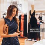 Woman texting on the phone while shopping in a clothing store.