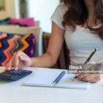 woman using calculator and make note calculate about cost at home.