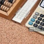 calculator, a wooden abacus and slide rule on a cork board