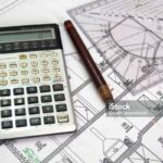 Architectural plan, pen, calculator and ruler close up.