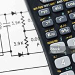 Looking down at a calculator, cropped, resting on a technical circuit diagram.