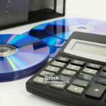Office supplies, calculator, compact discs on white desk