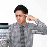 Disappointed Asian businessman with a calculator