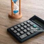 Black Digital Calculator with Sand Hourglass on Desk