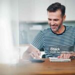 Smiling man using notebook and calculator to manage home budget
