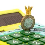 A 1 British pound coin in a gold crown and a calculator on a white background.