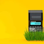 Calculator on grass isolated on orange background. 3d illustration