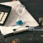 Time is money concept. Hourglass and calculator on the table.