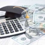 Small graduation cap on calculator, assorted cash