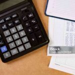 Flat lay of calculator with dairy and documents on the table.