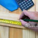 Measuring tape on wood plank view of carpenter work place with calculator